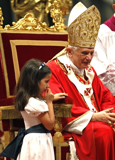 A young girl stands next to Pope Benedict XVI during a solemn mass to celebrate the feast of Saints Peter and Paul in Saint Peter's Basilica at the Vatican
